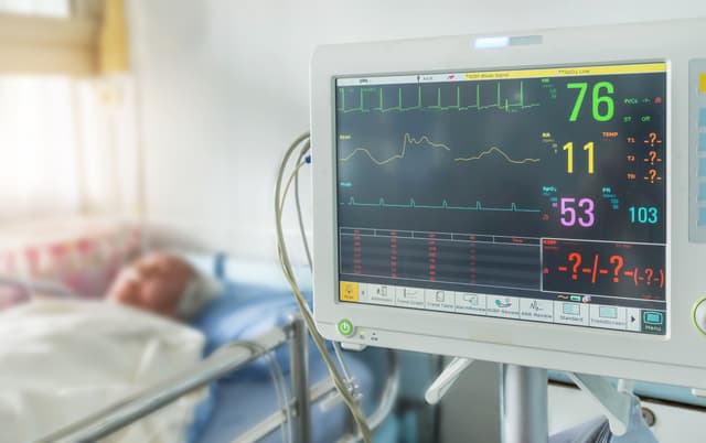 Person in hospital bed with vital sign readings showing | Image credit: ©Soontham stock.adobe.com