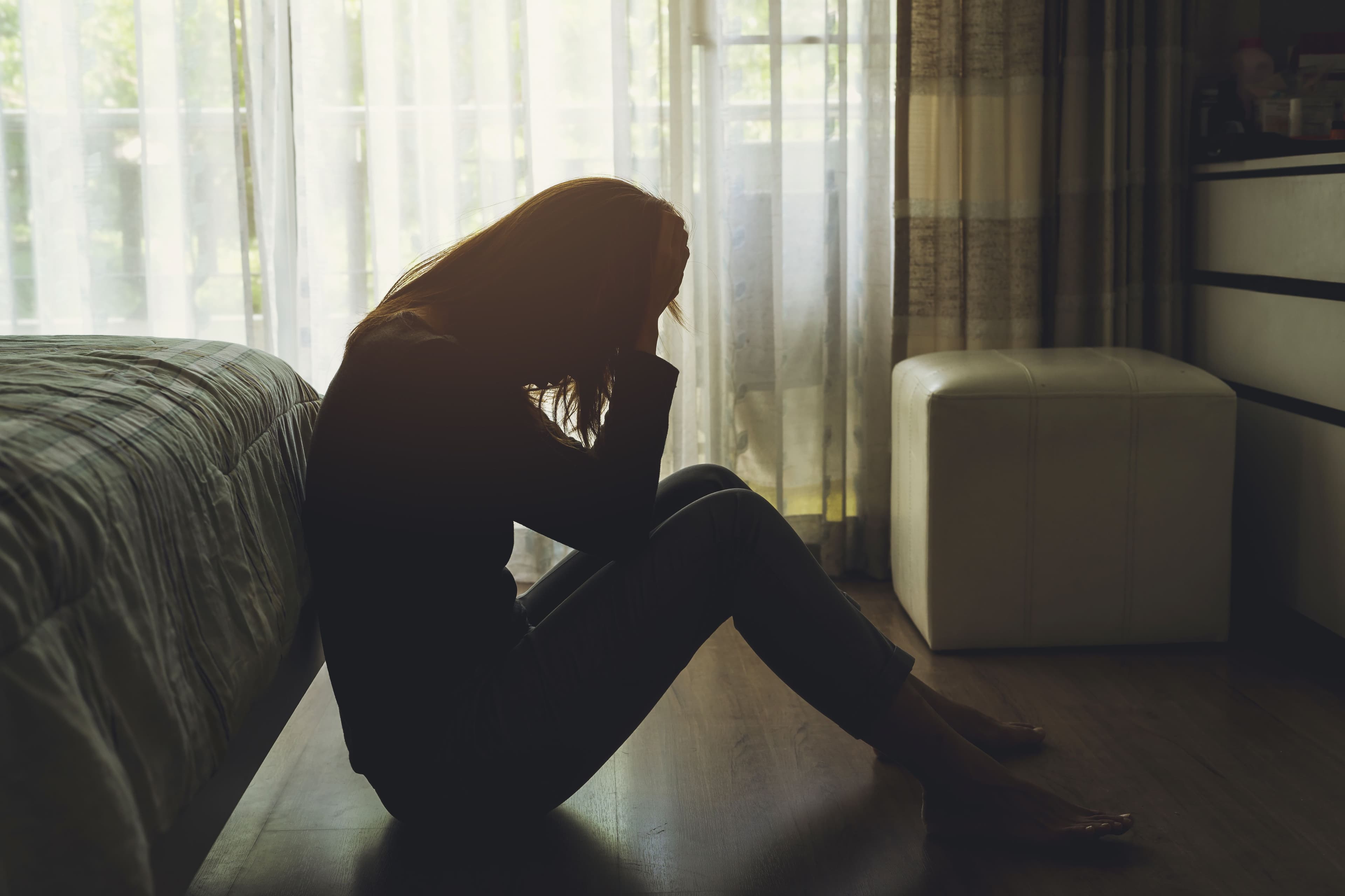 woman on floor looking sad silhouette | Image credit: @kittiplan stock.adobe.com